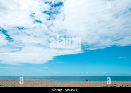 Florianópolis, Brasile. Februry, 2018. Un uomo, una donna e un cane sulla spiaggia, guardando l'orizzonte sul mare. Foto Stock