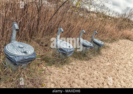 Quattro trash lattine sul bordo della zona di dune Foto Stock