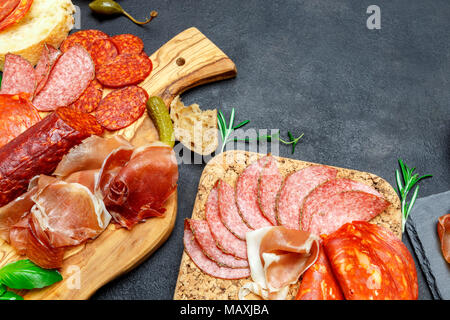 Tagliere con prosciutto, salame, grissini e olive Foto Stock