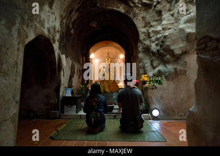 Famiglia in ginocchio a pregare per il Buddha in una grotta del tempio Wat Umong, Chiang Mai, Thailandia Foto Stock