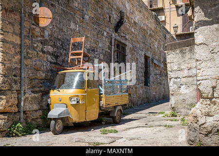 Un vecchio giallo Piaggio Ape nei vicoli di Palermo in Sicilia. Posti a sedere extra sulla parte superiore! Foto Stock