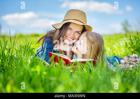 Madre e figlia giacente sul verde erba buona lettura prenota Foto Stock