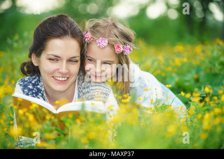 Madre e figlia giacente sul prato primavera godetevi la lettura prenota Foto Stock