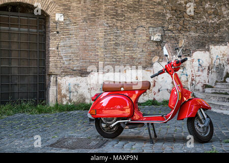 Un moderno rosso scooter Vespa parcheggiata su una strada a ciottoli nella zona di Trastevere a Roma, Italia. Foto Stock