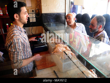 Ghouta orientale, Siria. 5 apr, 2018. La gente compra il pollo crudo in ha recentemente ripreso la città di Ayn Tarma nella parte orientale di Ghouta campagna di Damasco, Siria, il 5 aprile 2018. L'ultimo dai ribelli nella zona della capitale Damasco Ghouta orientale campagna sta per cadere con un nuovo accordo che vedrà la evacuazione dei ribelli dell Esercito di Islam verso il nord della Siria. Credito: Ammar Safarjalani/Xinhua/Alamy Live News Foto Stock