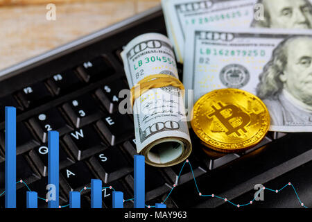 Golden dogecoin cryptocurrency gold coin Bitcoin giacente su una pila di US dollar cash banconote, accanto a un PC nero della tastiera del computer Foto Stock