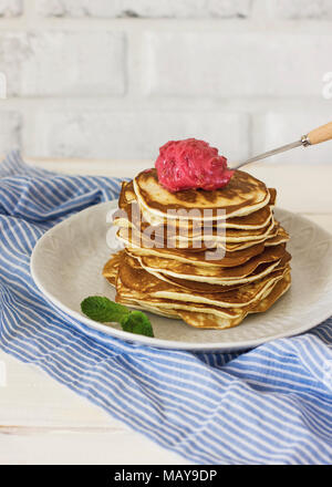 Pila di freschi di forno pancake con menta in piastra bianca in lino blu su sfondo bianco Foto Stock