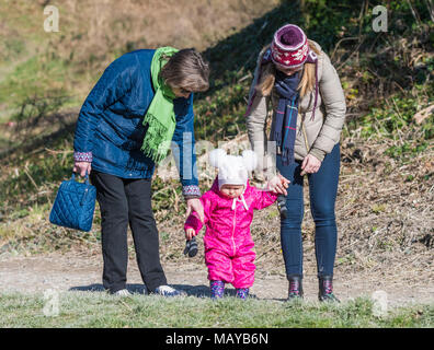 Baby tenendo le mani con 2 donne durante la deambulazione. Eventualmente i primi passi o ad imparare a camminare. Foto Stock