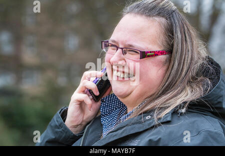 Giovane donna sorridente e cercando felice mentre si parla su un telefono cellulare. Concetto di felicità. Piacevole novità. Lieta notizia. Foto Stock