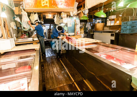 Tokyo, Giappone. La mattina presto nel mercato del pesce Tsukiji. Lavoratori la preparazione di tonno fresco in vendita. Foto Stock
