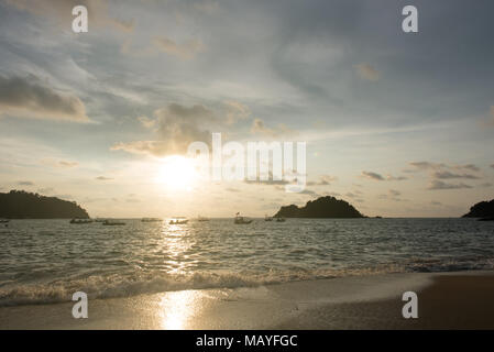 Vista di un Cielo di tramonto e silhouette di barche flottante e piccola isola sulla spiaggia come primo piano situato nell Isola di Pangkor, perak, Malaysia Foto Stock