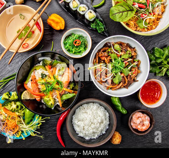 Cibo asiatico variazione con molti tipi di pasti. Kari riso, pasta e verdure. Vista superiore, servita sulla pietra nera. Foto Stock
