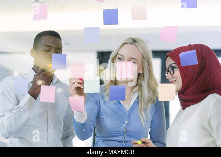 Creative team aziendale la scrittura su note adesive in ufficio. I colleghi di brainstorming sulle nuove idee di business in ufficio. Foto Stock
