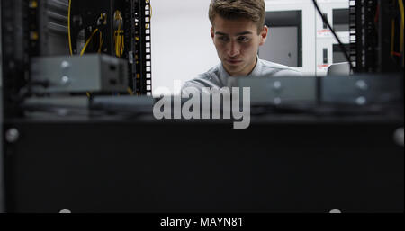 Il tecnico di eseguire le attività di manutenzione in una sala server rack Foto Stock