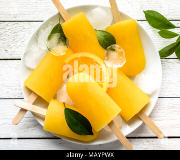 Orange popsicles bianco su sfondo di legno. In casa ice pops, vista dall'alto lay piatto Foto Stock