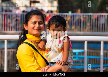 Giovane donna con sua figlia sorridente alla fotocamera, Imperatrice giardino a Pune Foto Stock