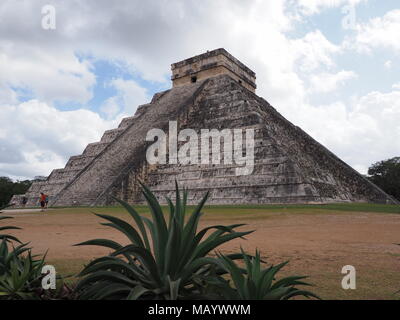 Piramide e agavi in Chichen Itza città Maya in Messico, rovine di siti archeologici paesaggi con nuvoloso cielo blu nel 2018 caldo e soleggiato giorno d'inverno, Foto Stock