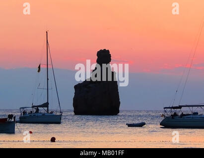 Tramonto di scena a Spiaggia Benirras, Isola di Ibiza. Formazione di roccia e sunbeam, vacanze estate scena. Foto Stock