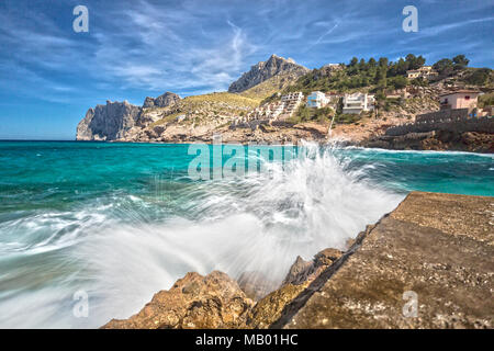 Gli spruzzi di acqua sul molo della piccola cittadina di Cala Sant Vincenc Foto Stock