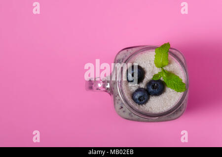 Frullato di mirtilli con menta in mason vasetto di vetro con bacche e foglie di menta. Al di sopra di vista sulla tabella di rosa. Cibo sano. Foto Stock
