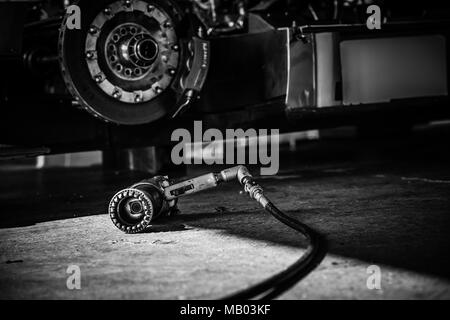 Bianco & Nero immagine astratta di LMP1 Le Mans Prototype pistola ruota sulla fossa pavimento del garage durante il Master Racing storica giornata di test sul circuito di Brands Hatch Foto Stock