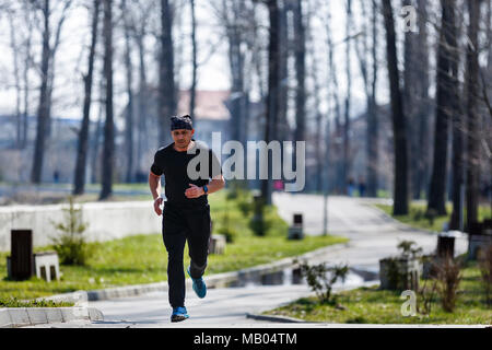 Un uomo di mezza età che corre attraverso il parco Foto Stock