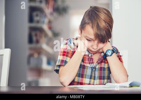 Imparare a casa. Little Boy facendo difficili compiti di matematica. Foto Stock