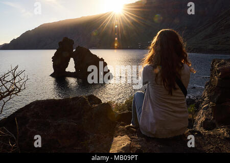 Donna seduta a guardare un tramonto vista panoramica di Roque de Bonanza isolotto di El Hierro, Isole Canarie, Spagna Foto Stock