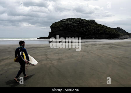 Bethells Beach, Nuova Zelanda - 14 Novembre 2017: un surfista presso la splendida spiaggia Bethells noto anche come Te Henga Beach. Foto Stock