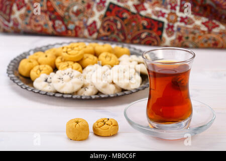 Tradizionali dolci iraniano di forma rotonda cookie di ceci pasticcini e biscotti di riso in persiano Toreutic piastra con un'immagine ravvicinata della coppa in vetro e sauc Foto Stock