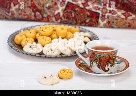 Tradizionali dolci iraniano di forma rotonda cookie di ceci pasticcini e biscotti di riso in persiano Toreutic piastra con un'immagine ravvicinata di design paisley cup Foto Stock