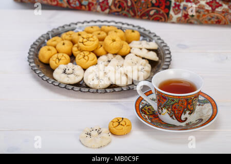 Tradizionali dolci iraniano di forma rotonda cookie di ceci pasticcini e biscotti di riso in persiano Toreutic piastra con un'immagine ravvicinata di design paisley cup Foto Stock