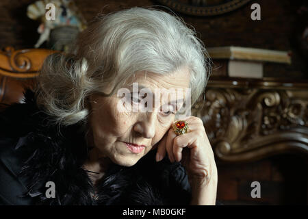 Ritratto di triste donna senior in boa in posa Foto Stock