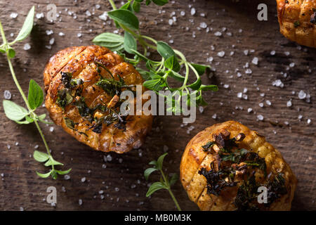Fisarmonica patate al forno con diverse erbe aromatiche e sale marino su legno sfondo rustico Foto Stock