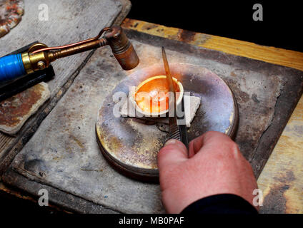 Close-up del lavoro di un gioielliere. Oro di fusione in una ciotola con un bruciatore. Foto Stock