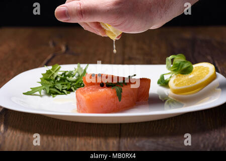 Gocce di succo di limone cadono su pezzi di salmone Foto Stock