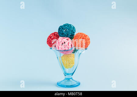 Gelato il gelato con colorati gelato palline fatte di sfere di rattan in coppa contro pastello blu sullo sfondo la minima nozione. Foto Stock