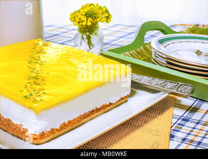 Tutto il limone fresco cheesecake mousse in una cucina estiva impostazione su una tabella con le piastre e forche spazio copia in background, Foto Stock