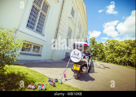 Appena sposata con segno e lattine su uno scooter Foto Stock