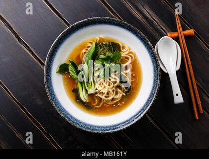 Ramen asian noodle in brodo con pak choi cavolo in ciotola di legno scuro dello sfondo Foto Stock