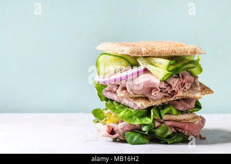 Manzo e verdure panini con affettati, Cetriolo, Insalata verde, segale grano intero pane in pila sul grigio verde pin-up sullo sfondo di stile. Foto Stock