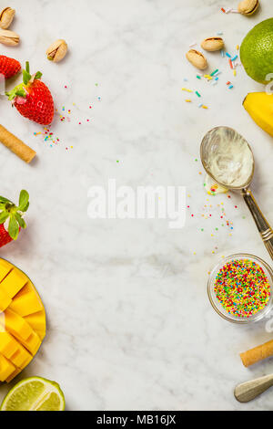 Ice Cream concetto. Vista superiore del gelato cucchiaio e ingredienti per gusti assortiti su marmo bianco dello sfondo. Piatto, laici copyspace Foto Stock