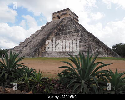 Piramide e agavi in Chichen Itza città Maya in Messico, rovine di siti archeologici paesaggi con nuvoloso cielo blu nel 2018 caldo e soleggiato giorno d'inverno, Foto Stock