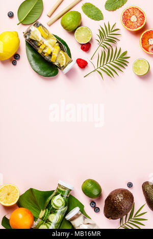 Detox infusi di frutta acqua, frutti tropicali e foglie di rosa su sfondo color pastello. Vista superiore, piatto laico, spazio per il testo Foto Stock