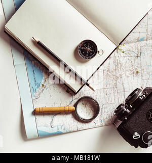 Preparazione per il viaggio. Mappa, notepad, fotocamera, Magnifier, bussola, matita e bicchieri. Vintage nei toni dell'immagine. Vista dall'alto. Lay piatto. Foto Stock