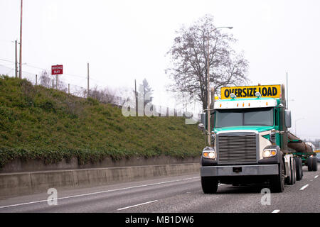 Potente American classic green big rig semi carrello trattore con segno sovradimensionare il carico sul tetto il trasporto di carico oversize sullo speciale semi rimorchio Foto Stock