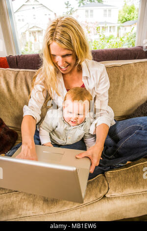 Un 30ish madre e il suo bambino suonare insieme con un computer portatile. Foto Stock