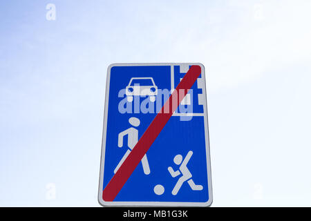 Segnale stradale che mostra un'auto, un bambino e un adulto attraversato da una linea rossa. Fine zona residenziale. Foto Stock
