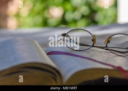 Vecchi occhiali bifocali giacciono sulla pagina biblica all aperto con camera per copiare il testo Foto Stock