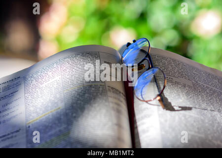 Vecchi occhiali bifocali giacciono sulla pagina biblica all aperto con camera per copiare il testo Foto Stock